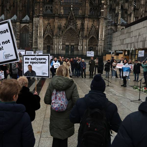 Menschen mit Plakaten stehen in Köln auf der Domplatte.