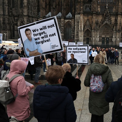Menschen mit Plakaten stehen in Köln auf der Domplatte.