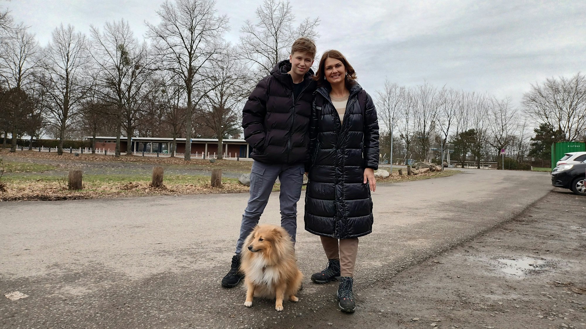Frau mit Sohn und Hund auf einem Spazierweg