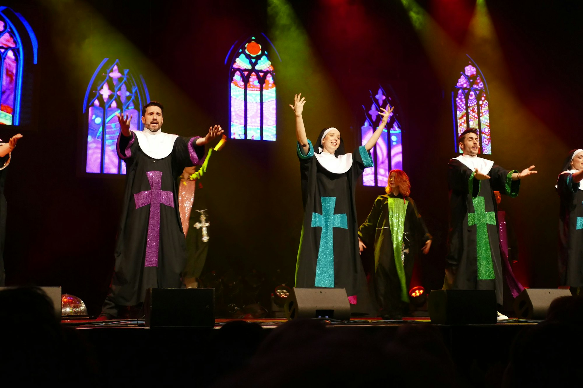 Sänger und Sängerinnentragen Nonnenumhänge mit bunten, glitzernden Kreuzen.