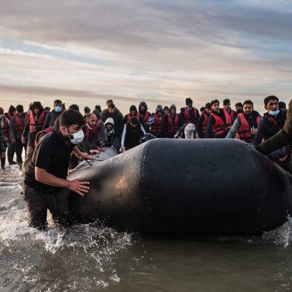 Migranten ziehen ein Schlauchboot aus dem Wasser am Strand von Gravelines.