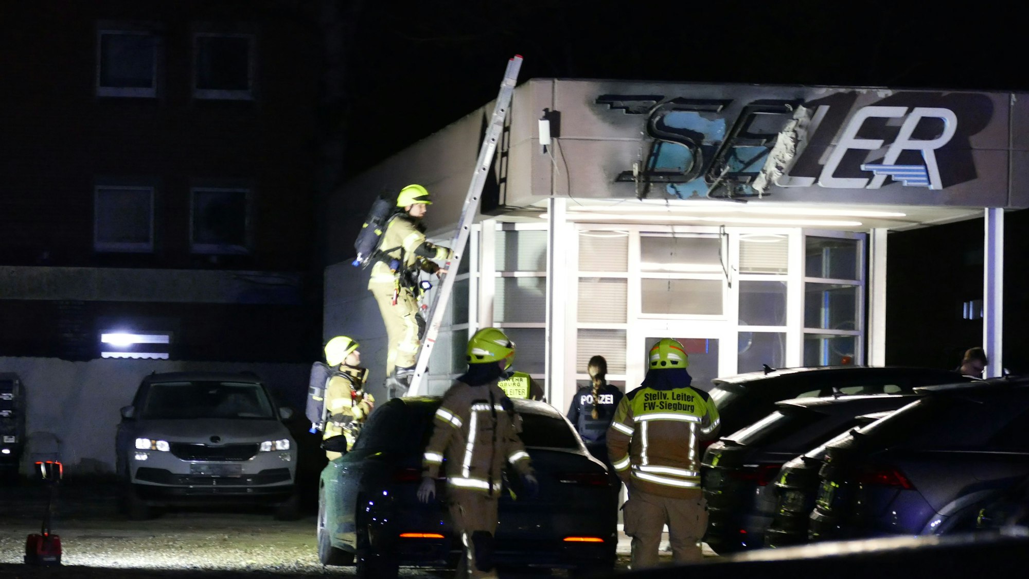 Feuerwehrleute auf einer Leiter an einem Dach eines Verkaufsbüros.