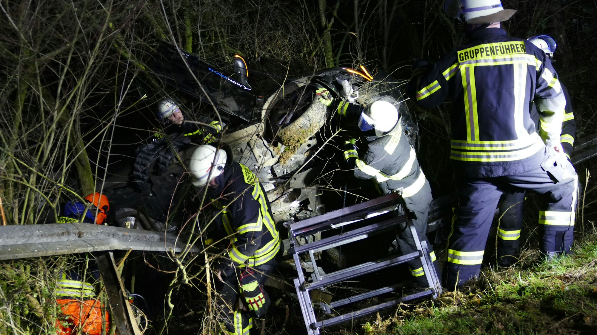 Feuerwehrleute untersuchen das Unfallauto.