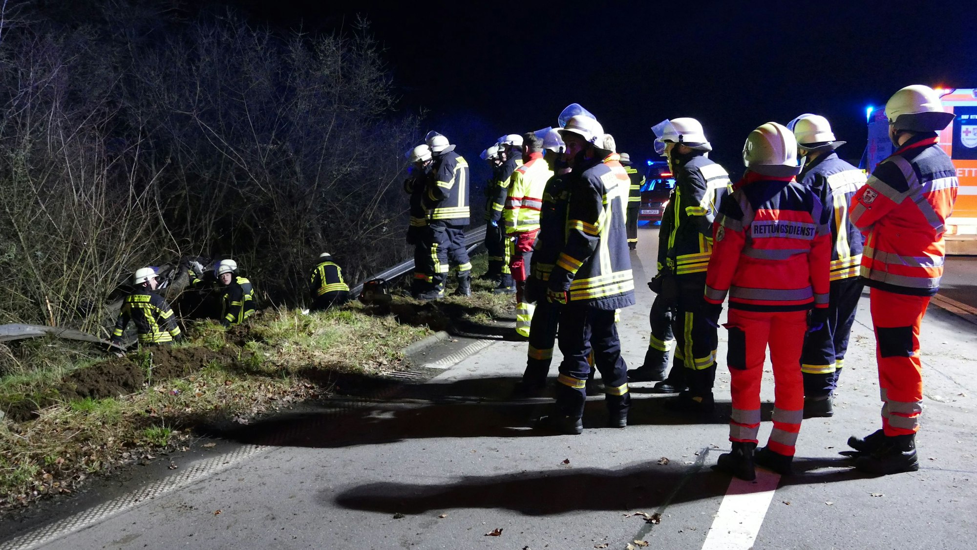 Rettungskräfte stehen bei Nacht auf einer Straße.