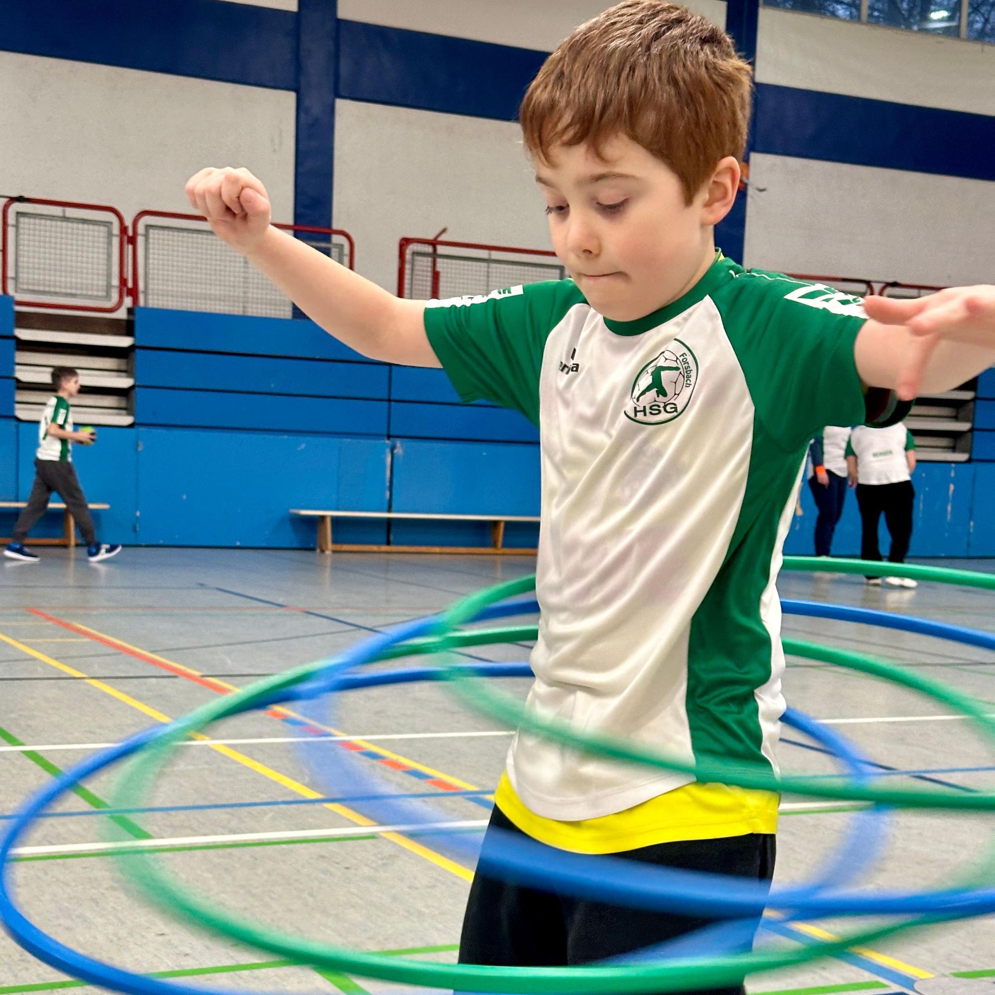 Ein Junge versucht drei Hula-Hoop-Reien zu ballacieren.
