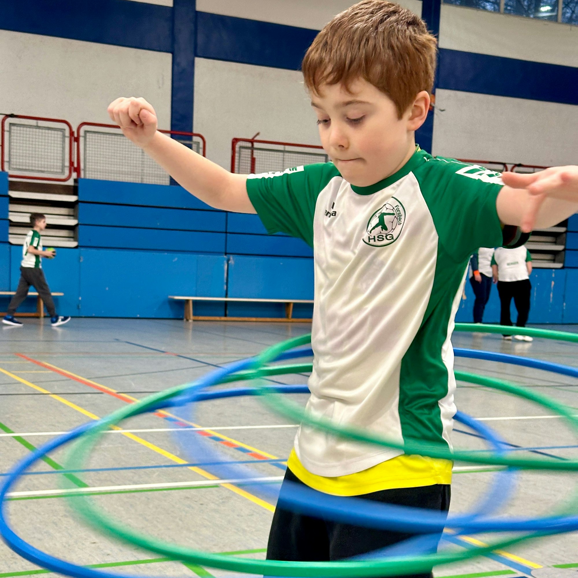 Ein Junge versucht drei Hula-Hoop-Reien zu ballacieren.