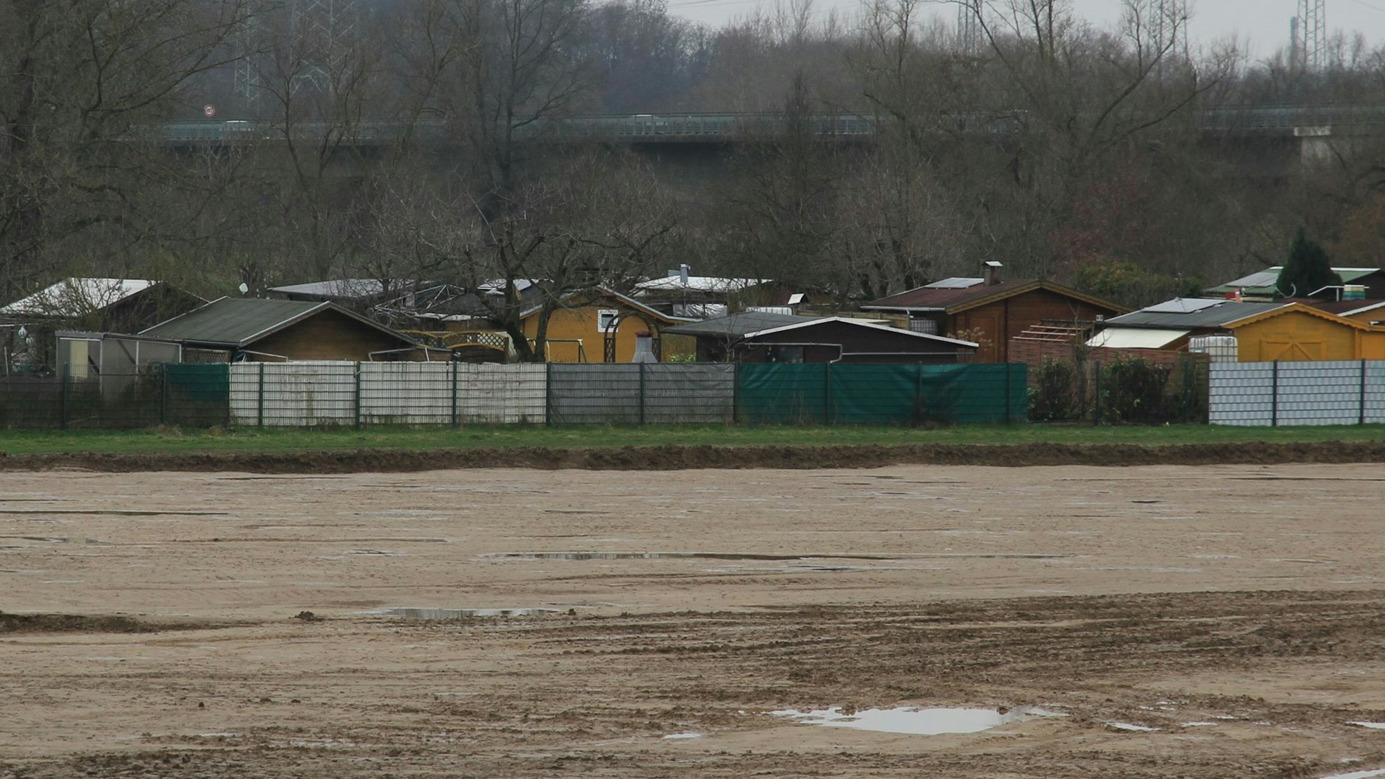 Schrebergärten neben einer großen Baugrube.