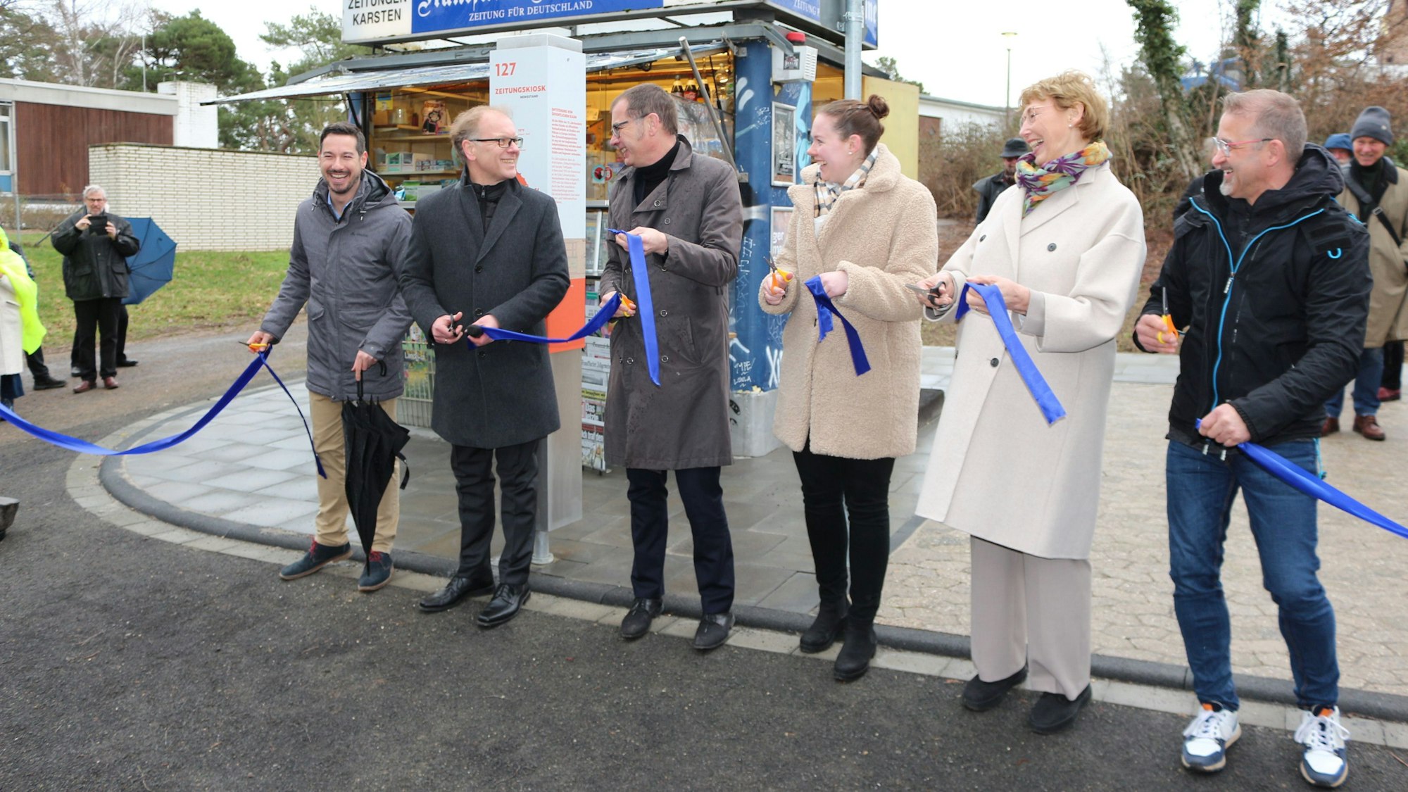 Zur Eröffnung des Zeitungskiosks im Freilichtmuseum Kommern durchtrennten einige Männer und Frauen symbolisch ein blaues Band.