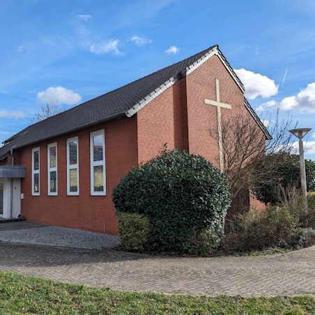 Die kleine Neuapostolische Kirche mit großem Kreuz an der Giebelwand und dem neugestalteten Eingangsbereich.