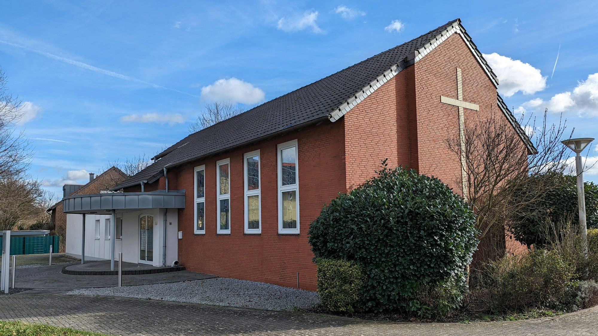 Die kleine Neuapostolische Kirche mit großem Kreuz an der Giebelwand und dem neugestalteten Eingangsbereich.
