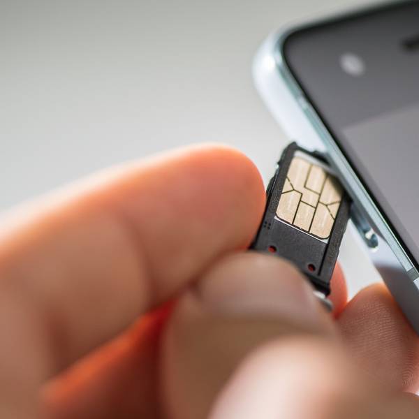 Eine Hand führt eine SIM-Karte in ein Smartphone ein.