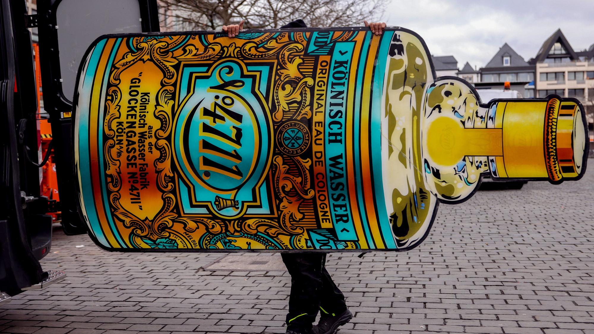 Ein Mitarbeiter verlädt die 4711-Flasche der Reklame in einen Firmenwagen.