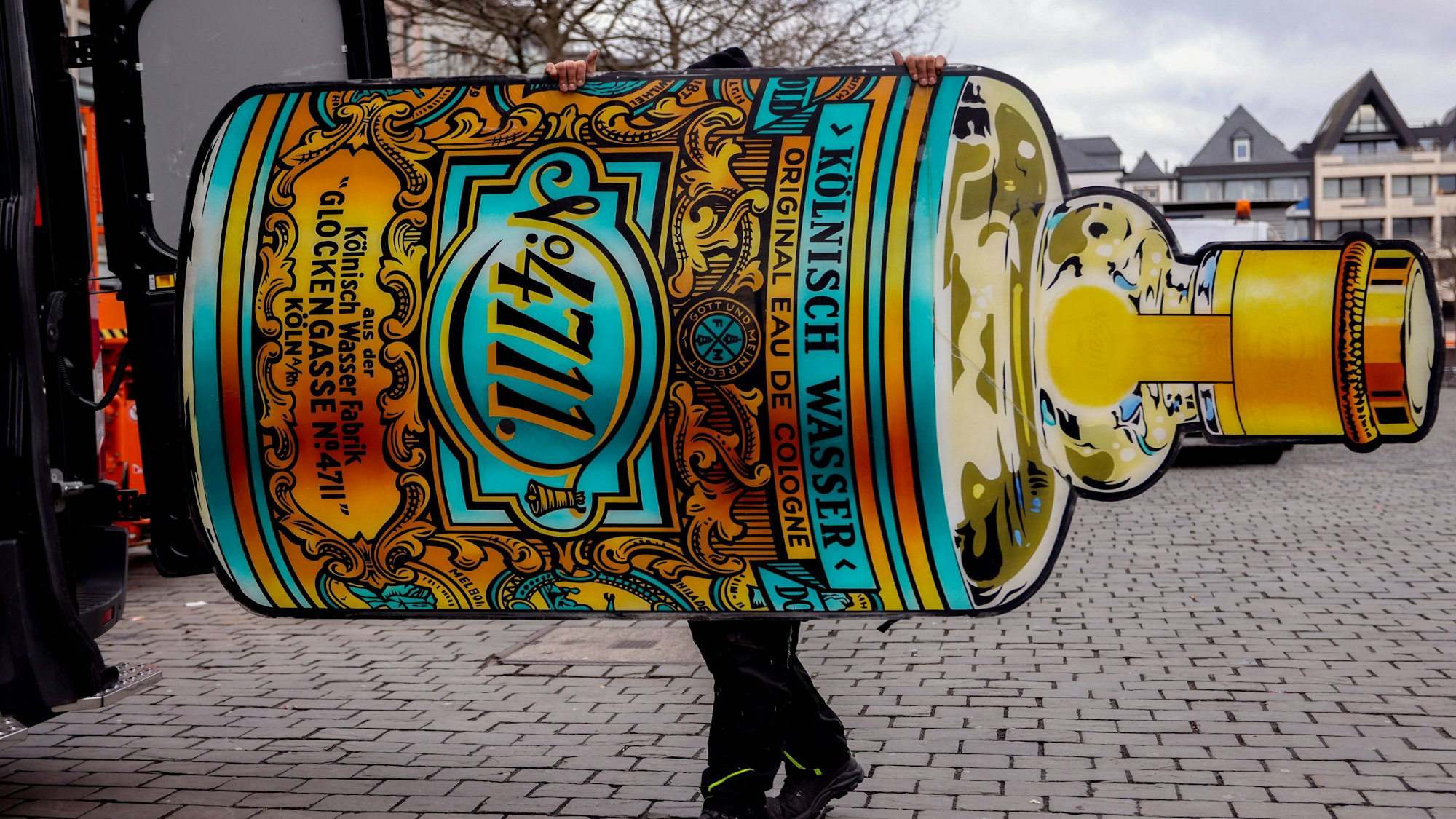 Ein Mitarbeiter verlädt die 4711-Flasche der Reklame in einen Firmenwagen.