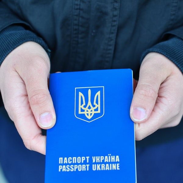 Ein Pass der Ukraine: das blaue Dokument wird von zwei Händen in die Kamera gehalten.