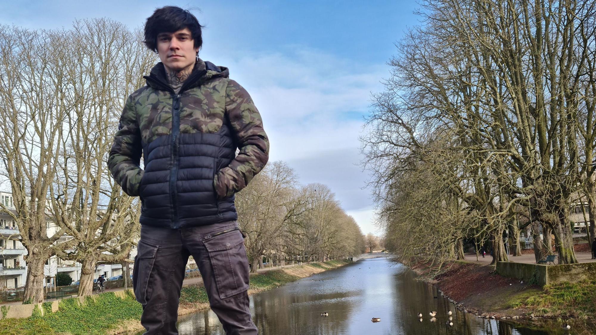 Ein junger Mann steht auf einer Beton-Brüstung, im Hintergrund ist der Lindenthaler Kanal zu sehen.