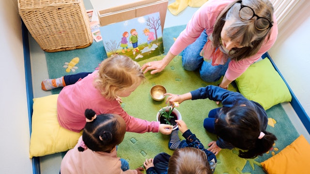 13.02.2024, Nordrhein-Westfalen, Dortmund: Erzieherin Petra Hahn betrachtet in der städtischen „Fabido-Kita Berliner Straße“ mit Ronja, Khadija, Milo und Alina ein Schneeglöckchen. Foto: Bernd Thissen/dpa