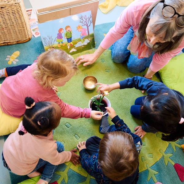 13.02.2024, Nordrhein-Westfalen, Dortmund: Erzieherin Petra Hahn betrachtet in der städtischen „Fabido-Kita Berliner Straße“ mit Ronja, Khadija, Milo und Alina ein Schneeglöckchen. Foto: Bernd Thissen/dpa