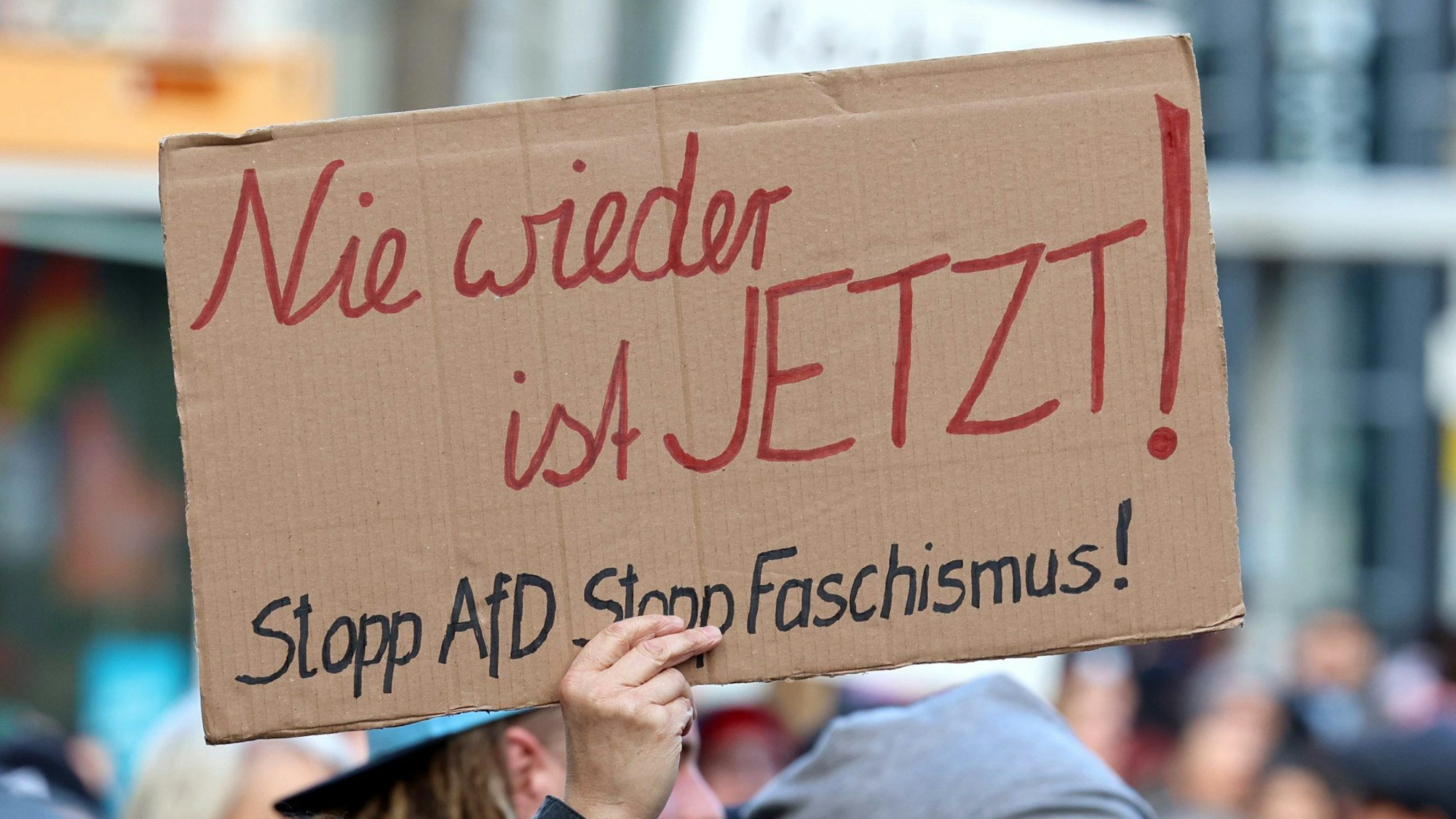 Ein Teilnehmer einer Demonstration gegen rechts hält vor dem Hauptbahnhof ein Schild auf dem „Nie wieder ist JETZT!Stopp AfD Stopp Faschismus“.