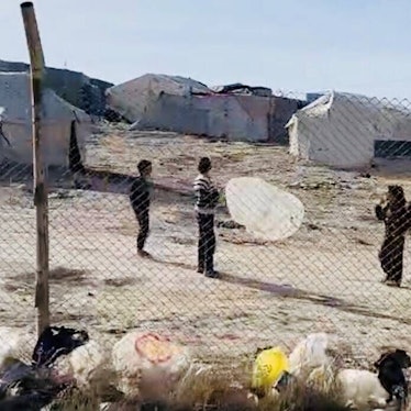 Ein Lager ist hinter einem Zaun auf kargem Boden zu sehen.