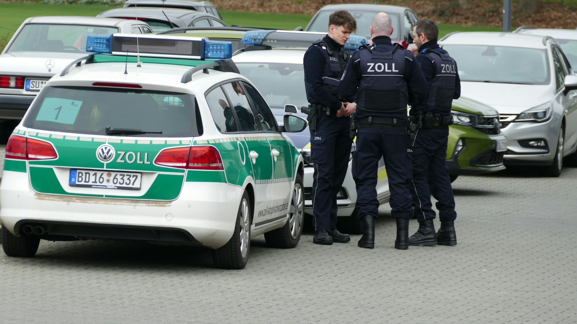 Zollbeamte stehen vor einem Auto des Zolls.