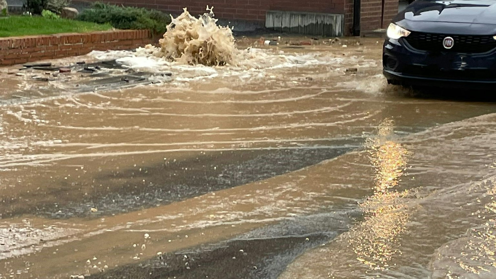 Auf dem Foto ist ein Auto zu sehen, das über die Straße fährt, auf der das Wasser steht.