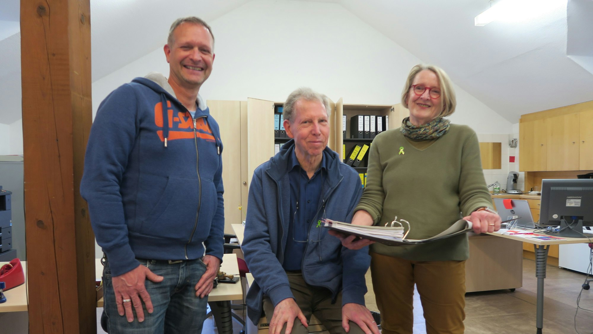 Eine Frau und zwei Männer in einem Großraumbüro