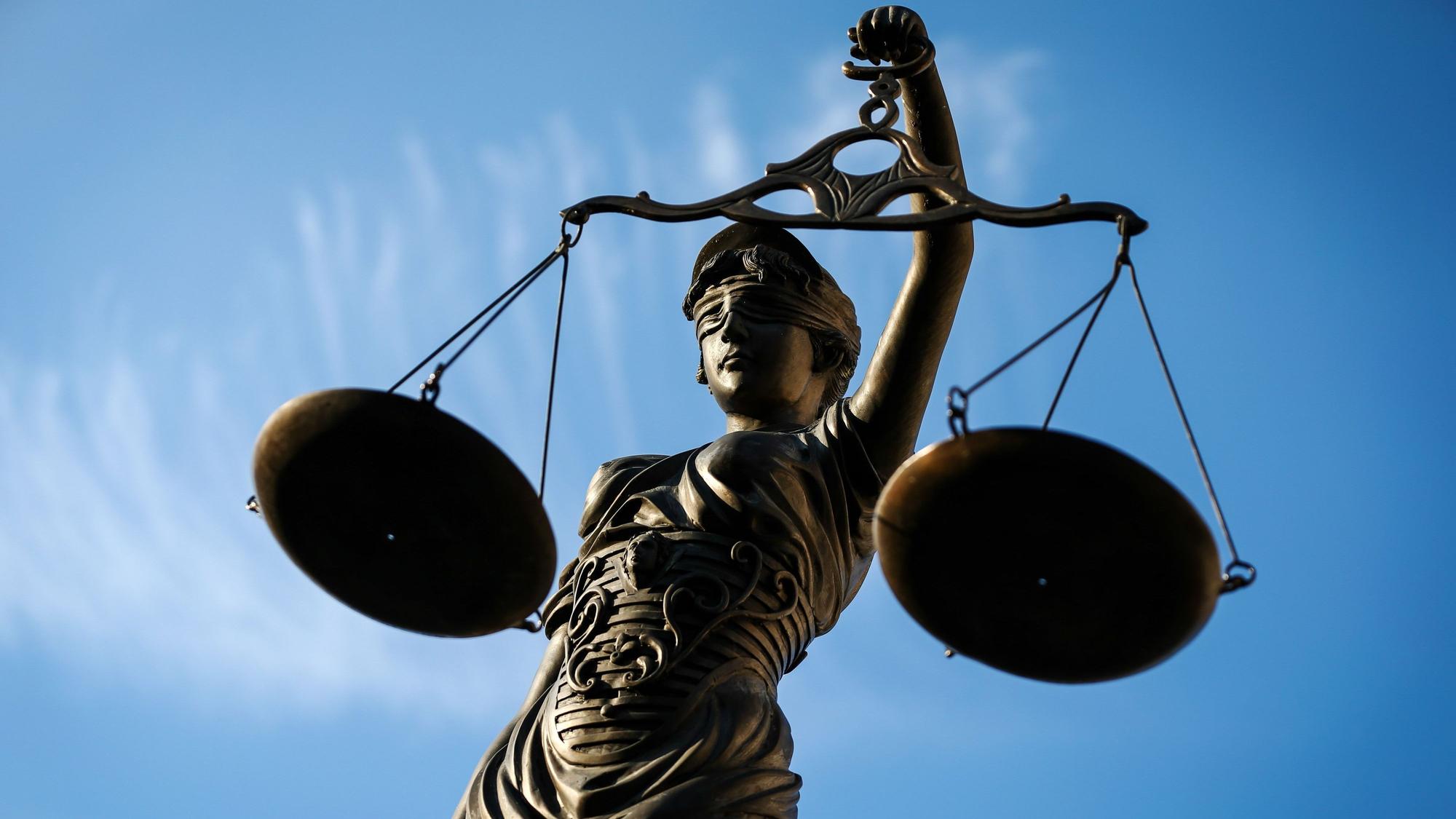 Eine Statue der Justitia hält eine Waage in der Hand.