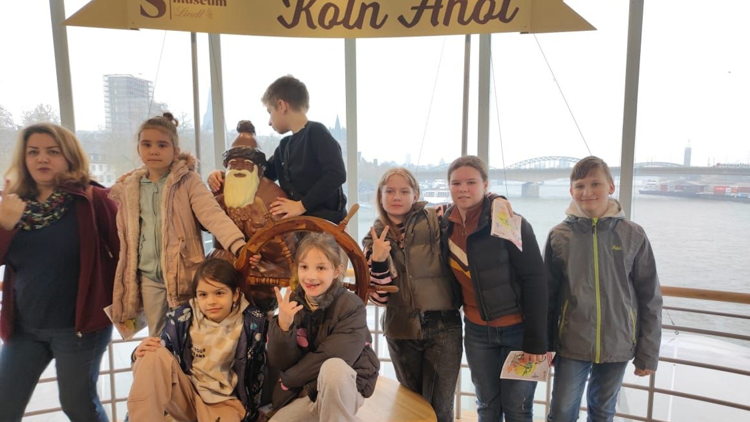 Sieben gehörlose und geflüchtete Kinder des Kölner Vereins Shahrzad stehen hinter einem Ruder im Kölner Schokoladenmuseum