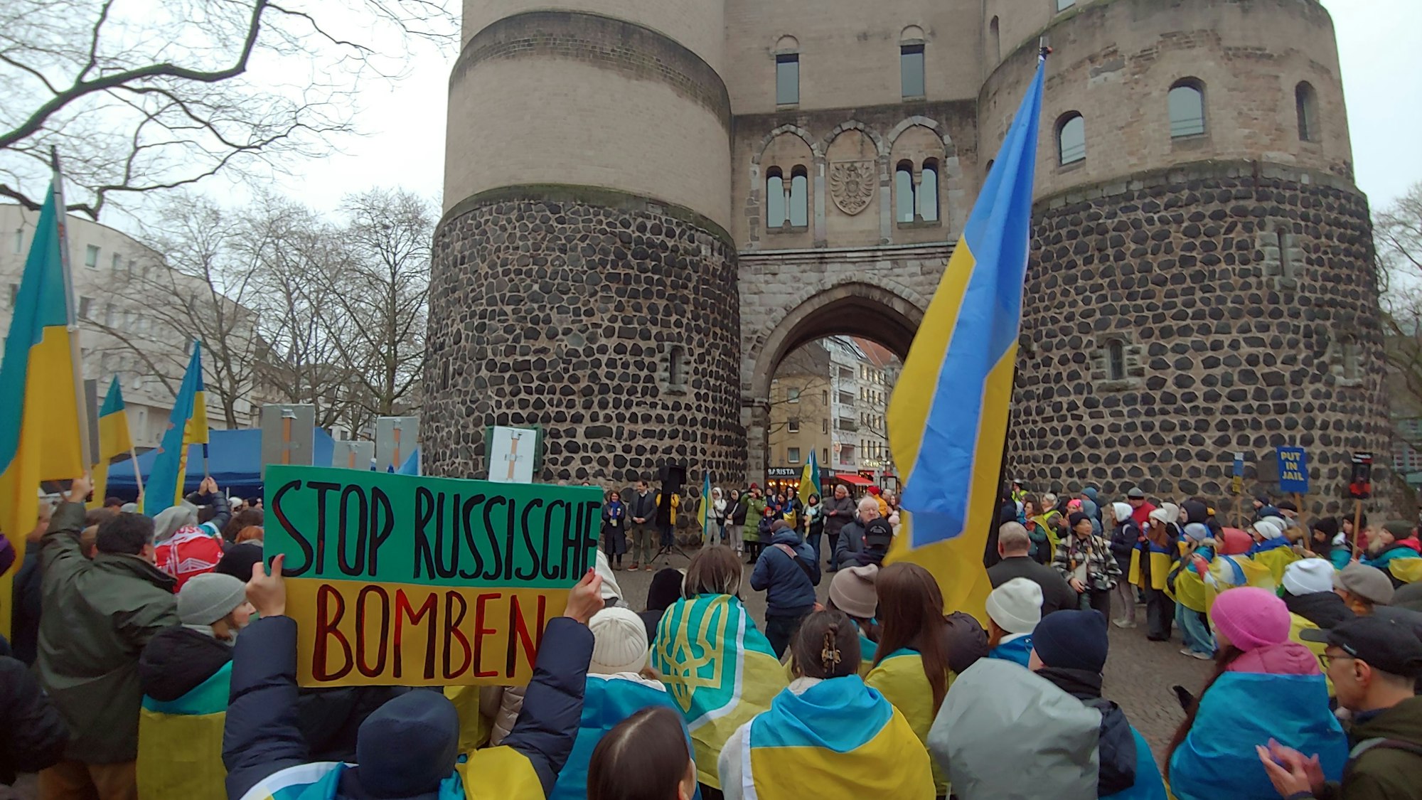 Zu sehen sind Menschen, die auf dem Rudolfplatz vor der Hahnentorburg für die Ukraine demonstrieren.