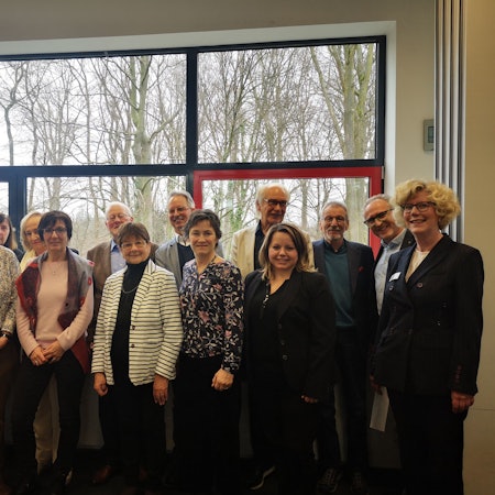 Mehrere Personen von karitativen Einrichtungen in Leverkusen und im Bergischen stehen als Gruppe vor einem Fenster.
