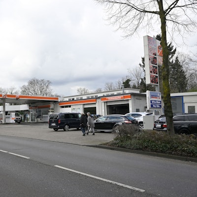 Zu sehen ist im Vordergrund die Fahrbahn, am Straßenrand befindet sich eine Tankstelle.