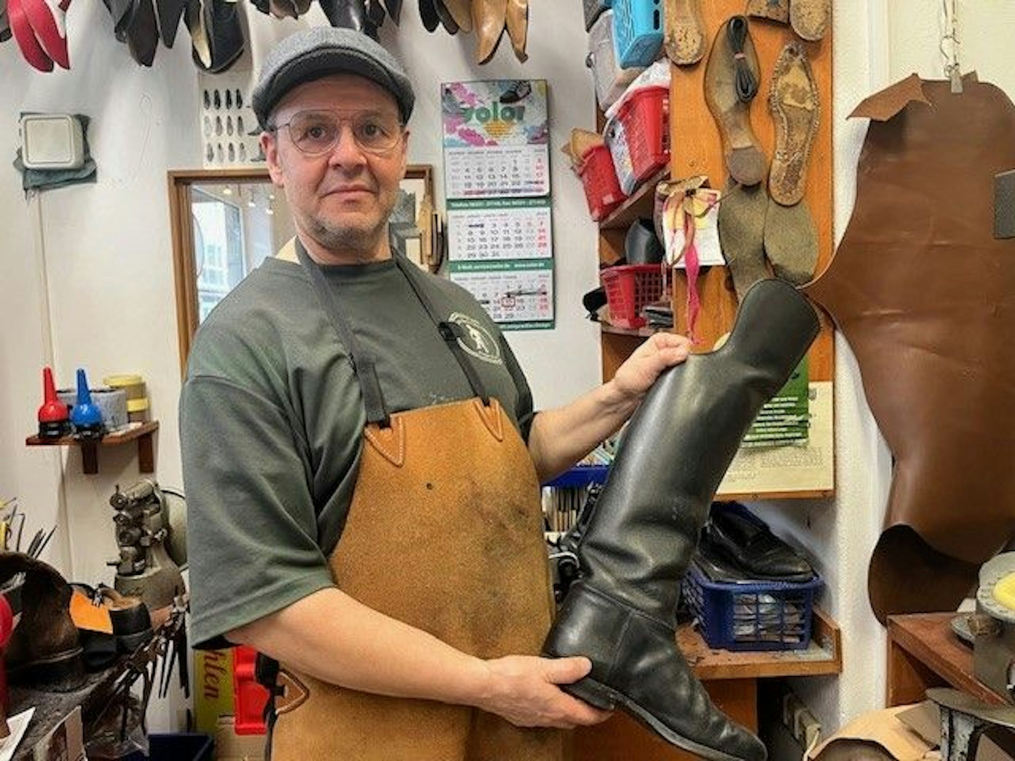 Schuhmacher Ralf Poppe zeigt einen Gardeschuh, den er reparieren wird.