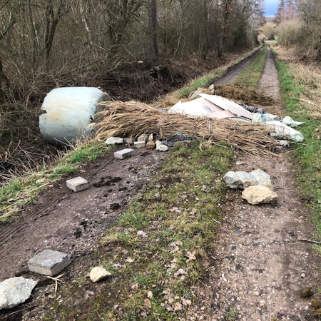 Auf einem Feldweg im Wäldchen des Kalkarer Moores liegt illegal entsorgter Müll.