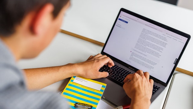 Ein Schüler eines Gymnasiums sitzt vor einem Laptop und benutzt ein KI-Tool.