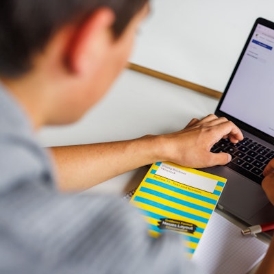Ein Junge sitzt vor seinem Laptop.