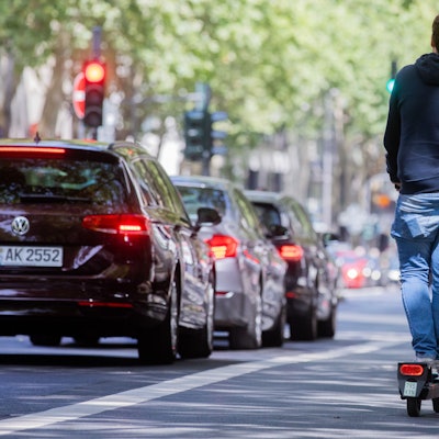 Ein Mann fährt auf dem Fahrradweg mit einem E-Scooter über den Kölner Ring.