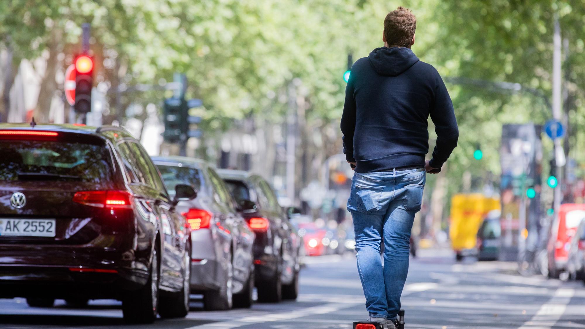 Ein Mann fährt auf dem Fahrradweg mit einem E-Scooter über den Kölner Ring.