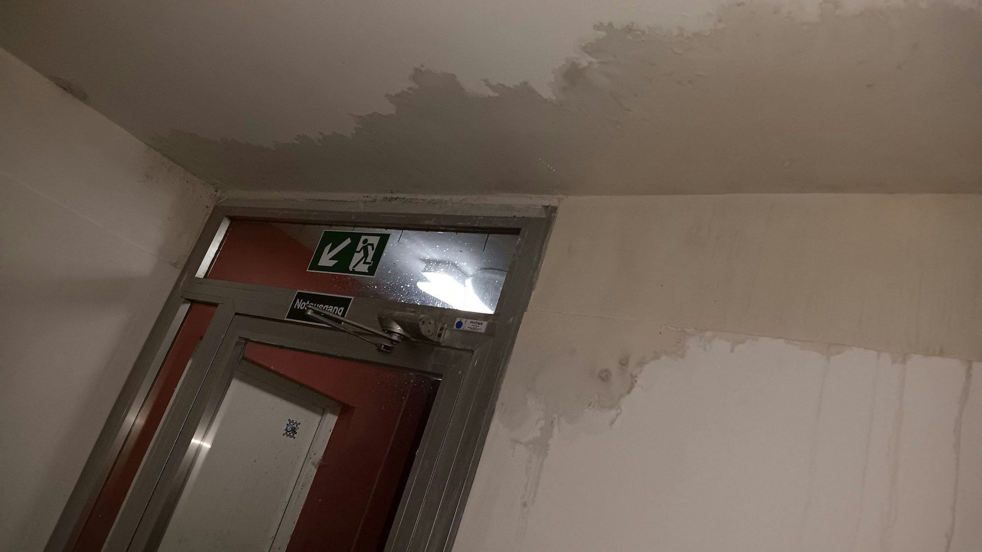 Ein großer Wasserfleck über einer Notausgangstür.