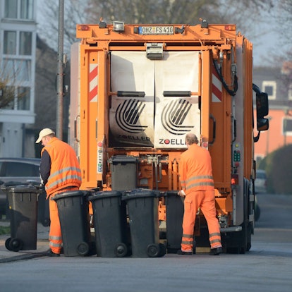 Zwei Männer von der Müllabfuhr entleeren Restmülltonnen.