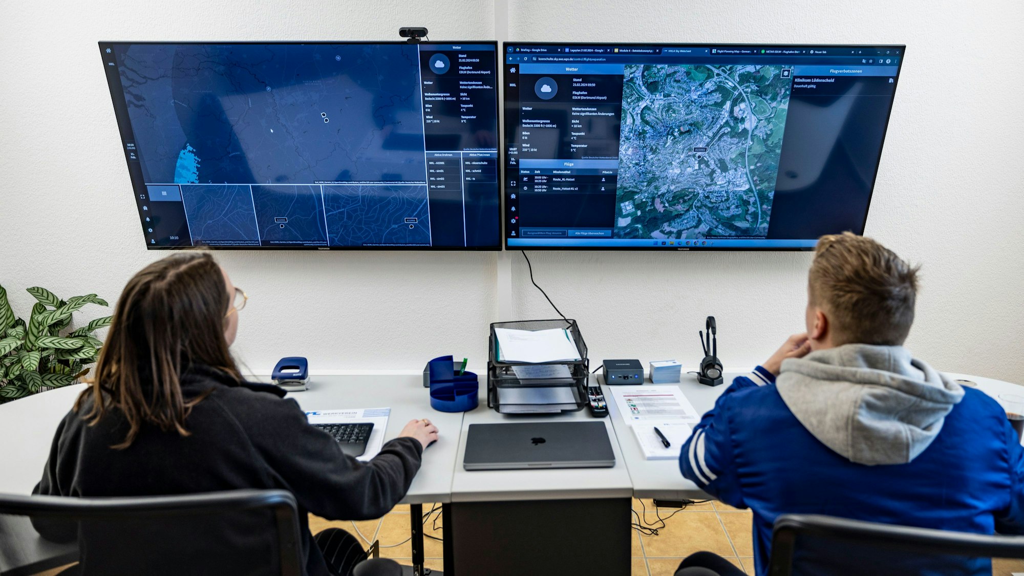 Piloten sitzen in einem Leitstand vor Bildschirmen, über die Lieferdrohnenflüge gestartet und überwacht werden.
