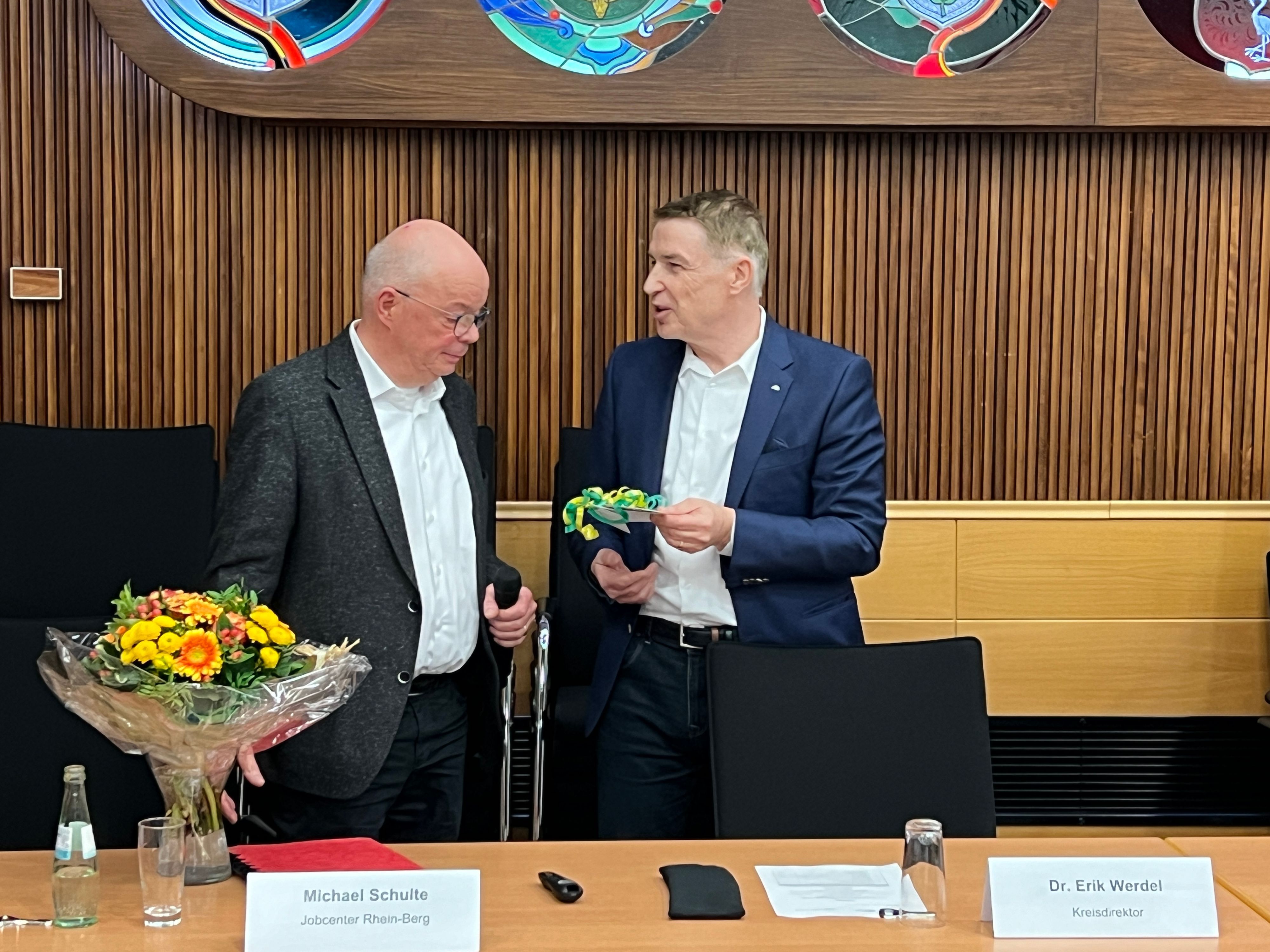 Kreisdirektor Dr. Erik Werdel (r.) überreicht im Kreis-Sozialausschuss den langjährigen Chef des Jobcenters, Michael Schulte, ein Geschenk.
