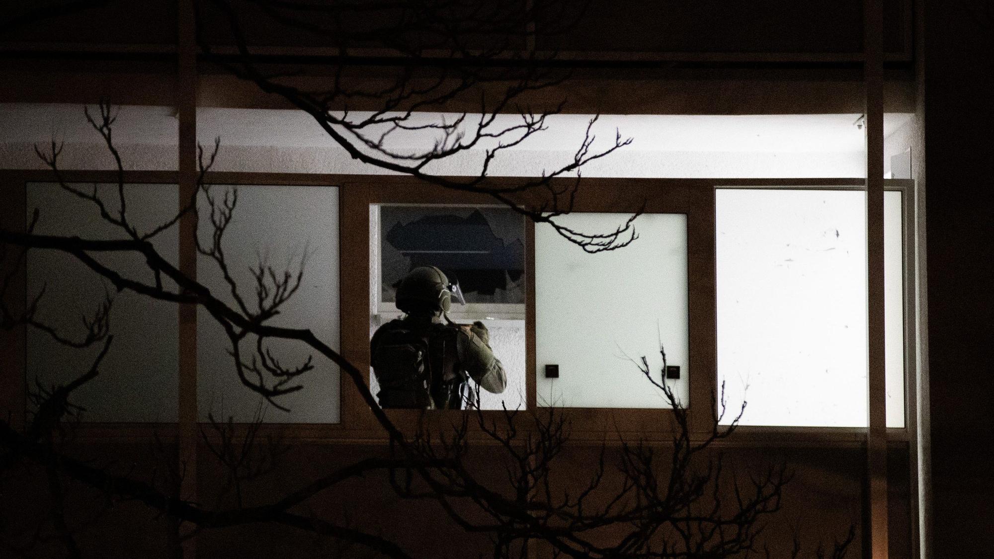 Einsatz in Düsseldorf: Ein Polizist steht vor einer zerbrochenen Fensterscheibe und fotografiert die Einsatzstelle.