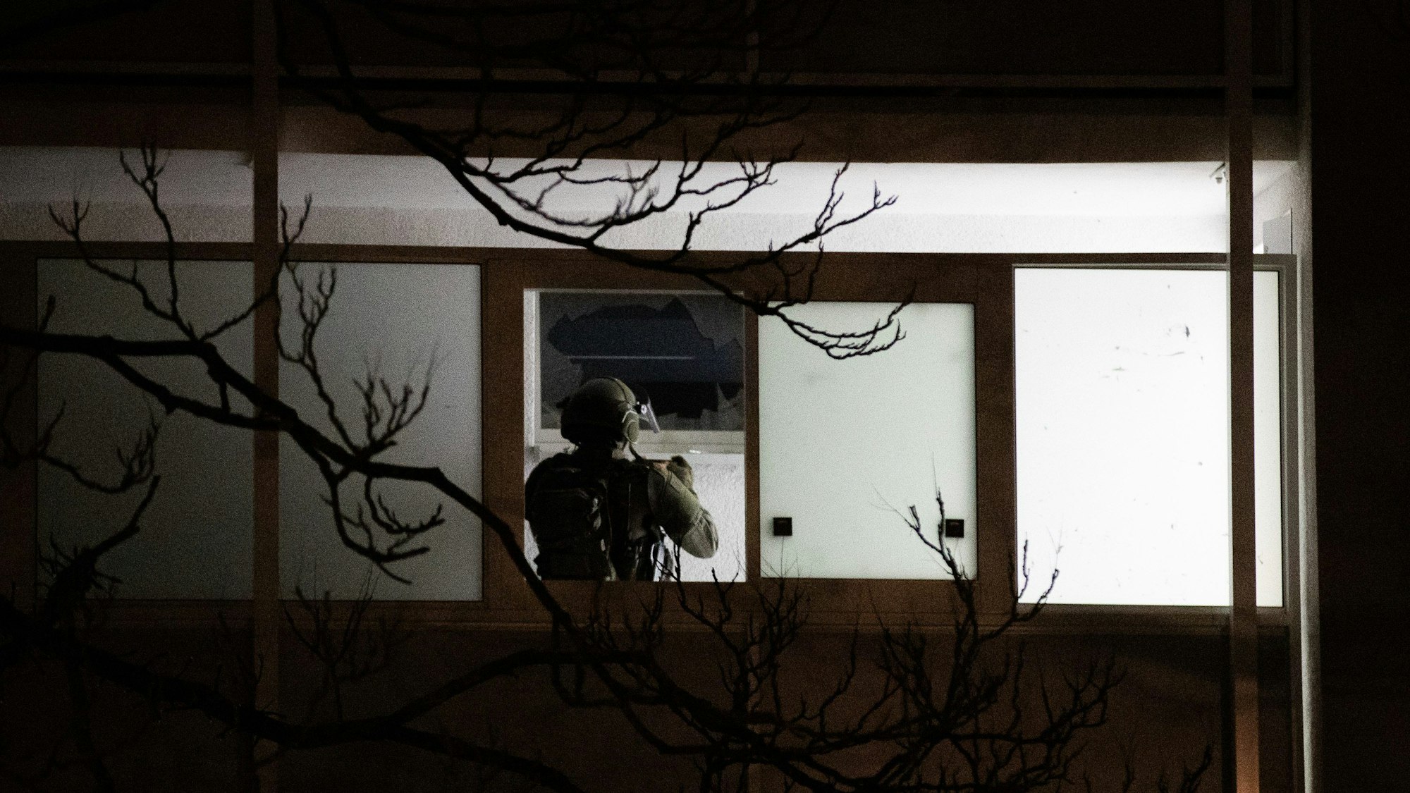 Einsatz in Düsseldorf: Ein Polizist steht vor einer zerbrochenen Fensterscheibe und fotografiert die Einsatzstelle.