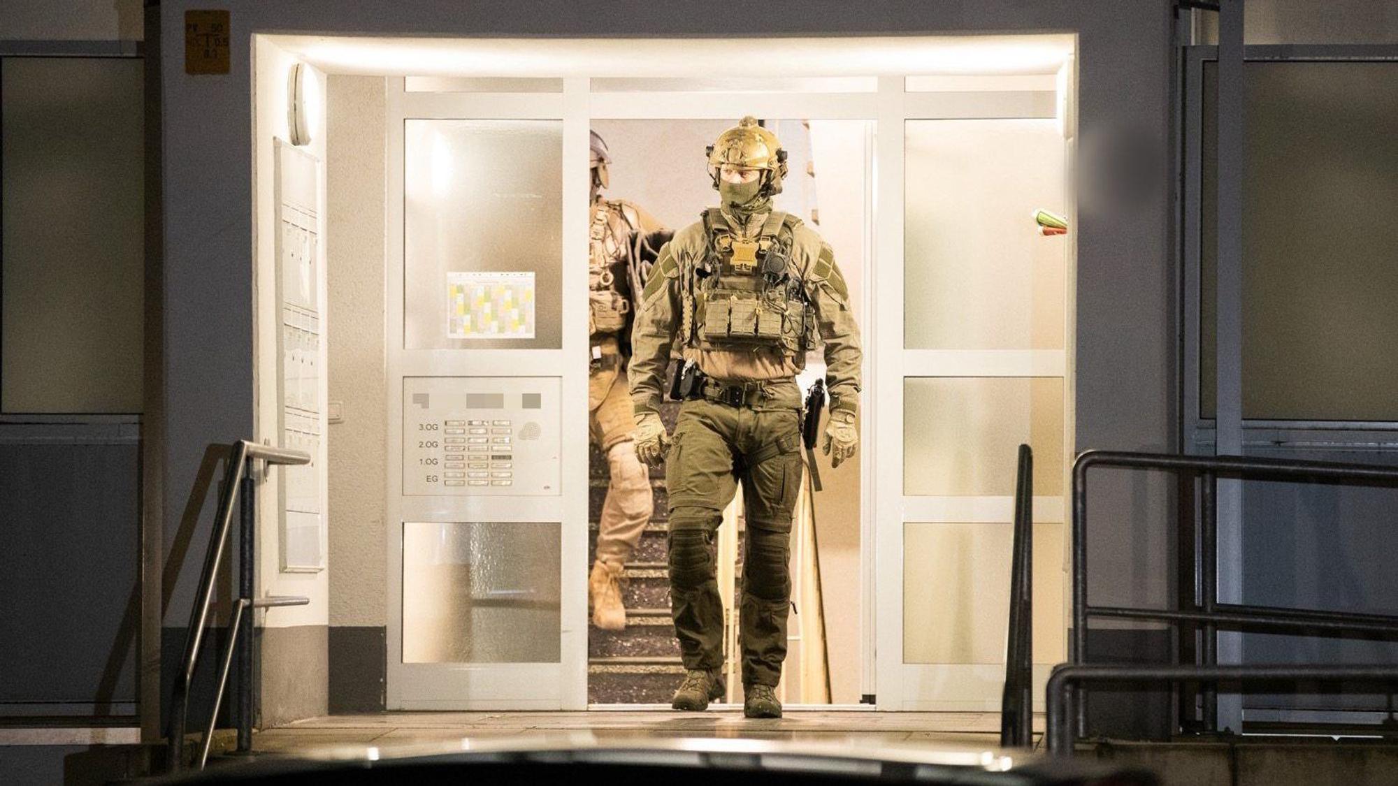 Einsatzkräfte der Polizei verlassen ein Gebäude. Bei einer großangelegten Razzia gegen Schleuser hat die Polizei mehrere Gebäude durchsucht.