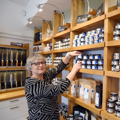 Eine Frau sortiert Gewürzdosen in einem Regal.