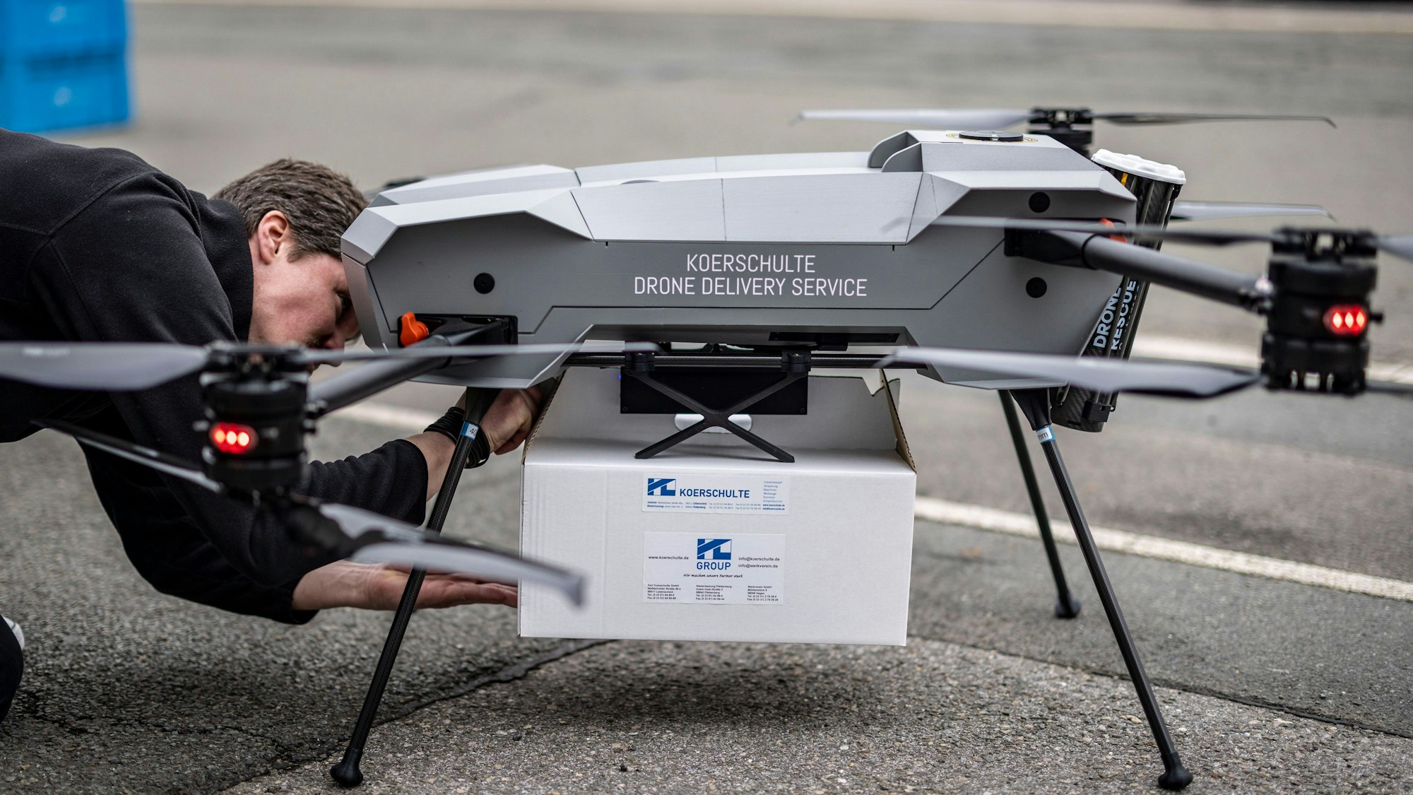 Ein Techniker befestigt das zu liefernde Paket an einer Drohne vom Hersteller Third Element Aviation aus Bielefeld.