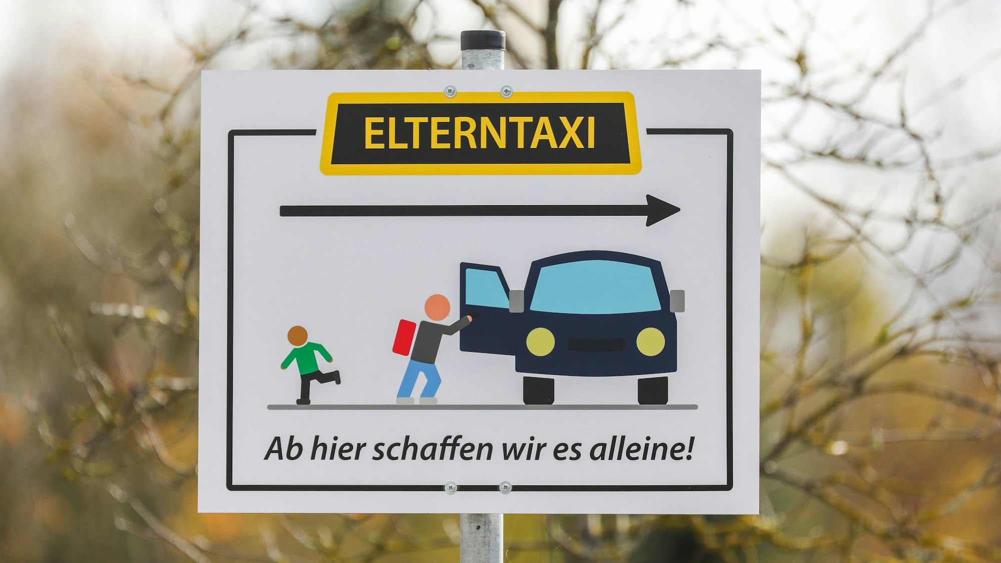Ein Schild steht am Parkplatz eines Schulgeländes.