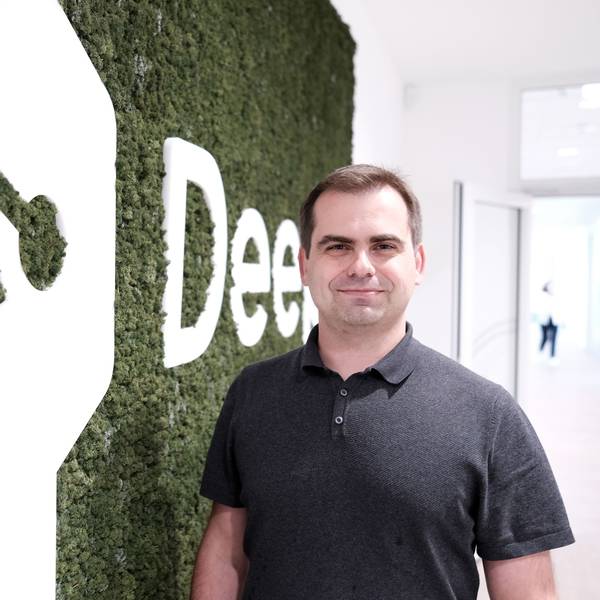 Jaroslaw Kutylowski, Chef von DeepL, steht in der Kölner Zentrale vor einem Logo der Firma.