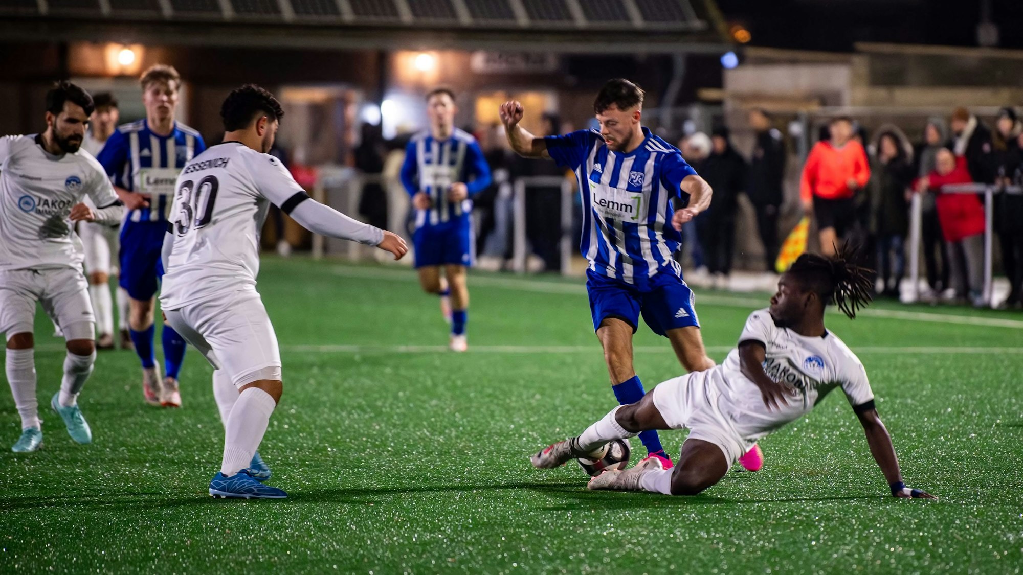 Samson Sayongo stoppt Ex-Mitspieler Nico Heuser mit einer fairen Grätsche.Enes Kiracti (30) sieht zu.