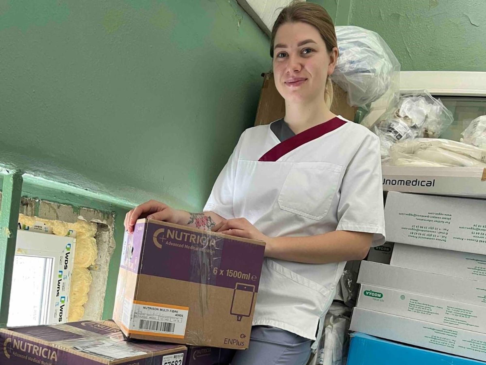 Eine junge Krankenschwester aus der Ukraine steht neben zehn Kisten mit Hilfsmitteln.